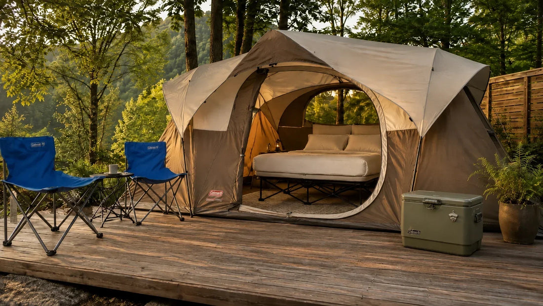 Glamping con casa de campaña Coleman, cama elevada, sillas plegables y hielera de acero en entorno boscoso.